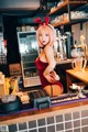 A woman in a red dress standing behind a bar.