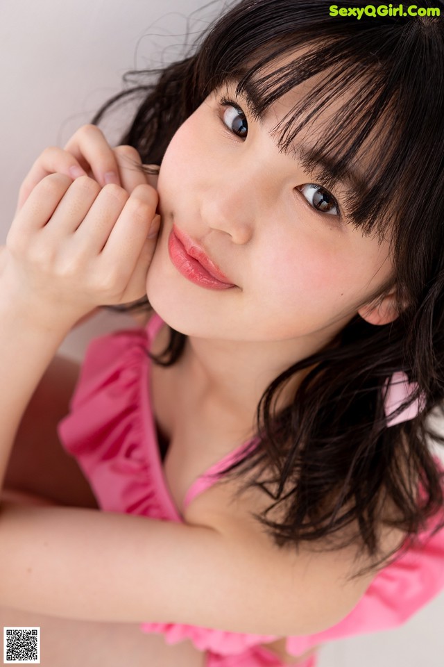 A young woman in a pink dress posing for a picture.