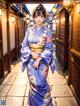 A woman in a blue kimono standing in an alleyway.