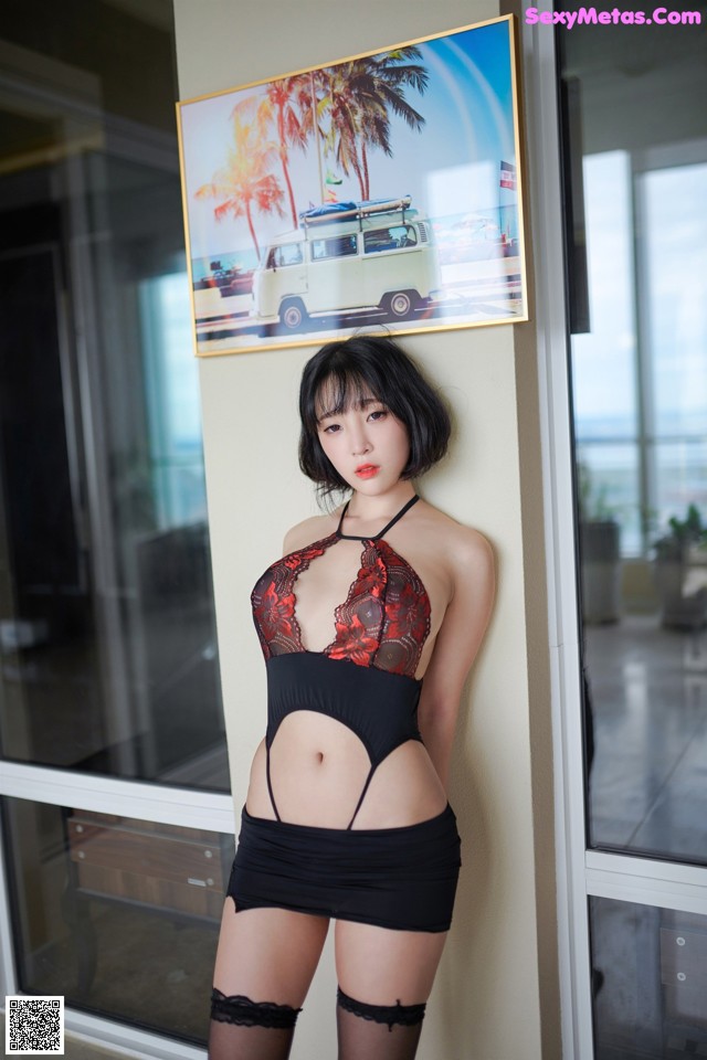 A woman in a black and red lingerie posing for a picture.