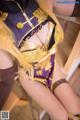 A woman in a purple and gold outfit sitting on a chair.