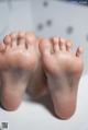 A pair of bare feet sitting on top of a bathtub.