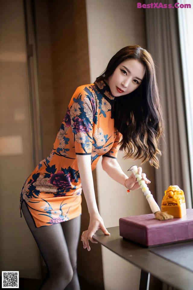 A woman in an orange dress cleaning a table with a brush.
