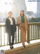 A couple of women standing next to each other on a bridge.