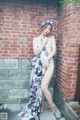 A naked woman standing in front of a brick wall.