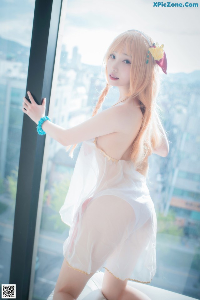 A woman in a white lingerie posing by a window.
