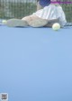 A woman sitting on a tennis court with her legs crossed.