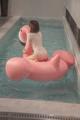 A woman sitting on an inflatable flamingo in a pool.