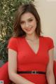 A woman in a red dress sitting on a red chair.