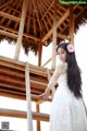 A woman in a white dress standing on a wooden structure.