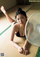 A woman laying on the floor next to a fan.